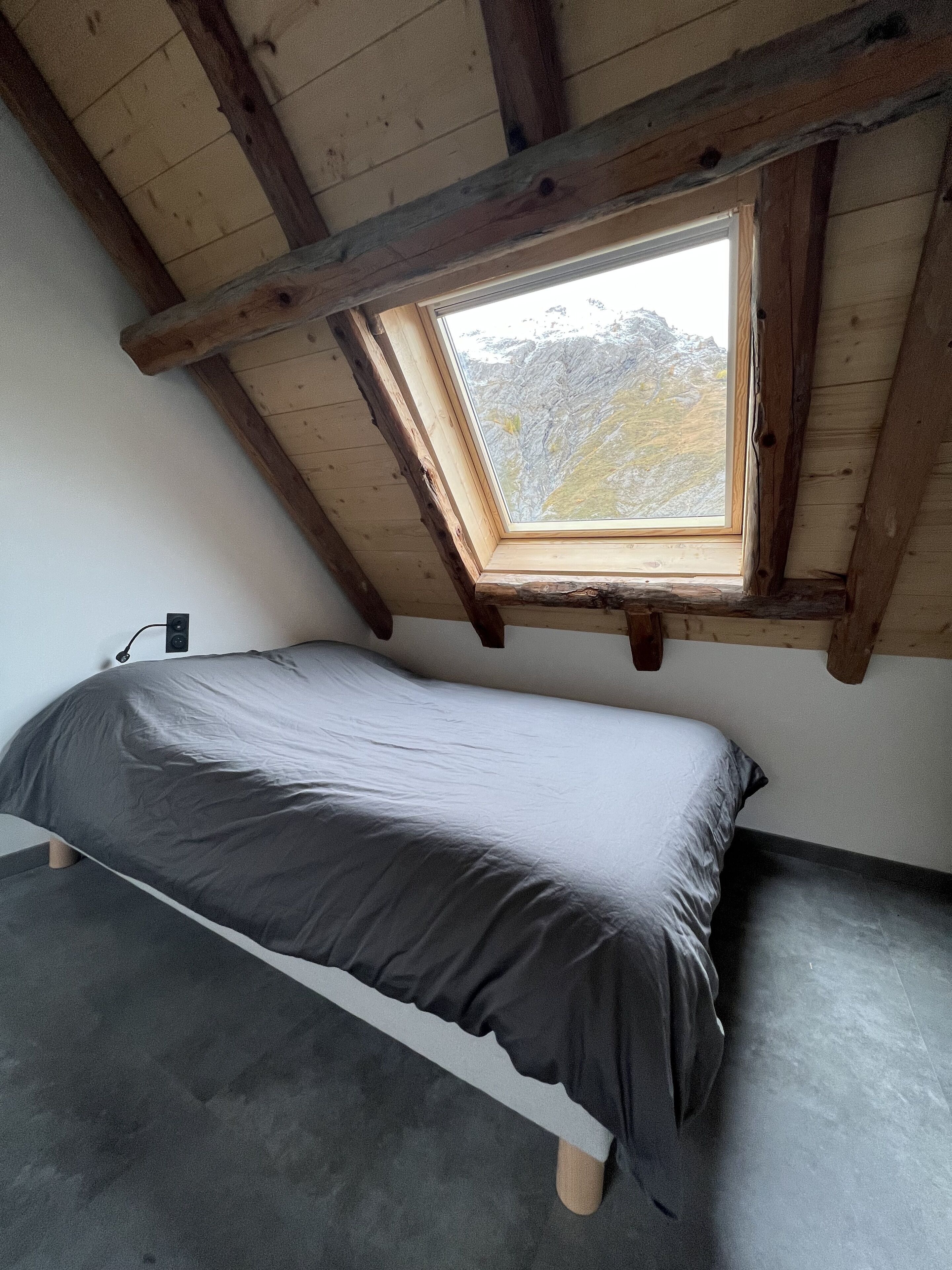 A small, single-bed room with a sloped ceiling and a skylight.