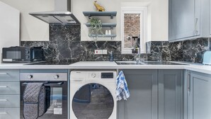 Une cuisine moderne équipée d’un lave-vaisselle, d’un four à micro-ondes et d’un lave-linge intégrés.