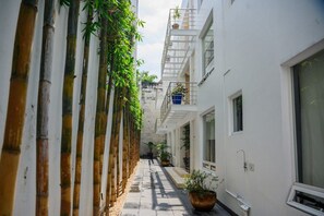 A narrow alleyway with a bamboo fence on one side and a white building on the other. - Condesa Residence Amsterdam 304 (Ciudad de México)
