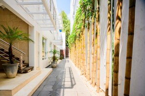 A narrow pathway flanked by buildings with a bamboo wall on one side and a staircase on the other. - Condesa Residence Amsterdam 304 (Ciudad de México)