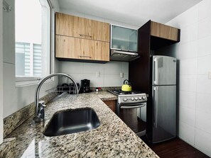 Eine moderne Küche mit Granit Arbeitsplatten, Edelstahlgeräten und Holzschränken.