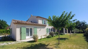 A house with a tiled roof, green shutters, and a small garden with a tree and shrubs. - La Bastide Saint Roch - Modern and spacious in a quiet location with a pool (La Tour-d'Aigues)