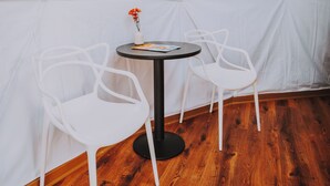 A room with a round table, two white chairs, a small vase with flowers, and a white tent-like structure in the background. - Apple Blossom Geodesic Dome at Starlight Haven Resort (Hot Springs)