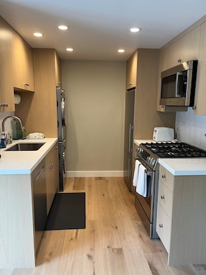 Een moderne keuken met houten kastjes, roestvrijstalen apparatuur en een zwart aanrecht.