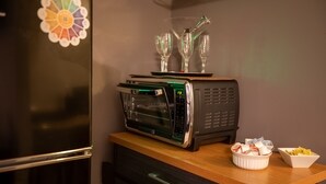 A kitchen with a toaster oven on a wooden countertop, a refrigerator, and a small bowl with snacks. - Luxurious Pool Cottage Sleep 2 (Port St. Lucie)