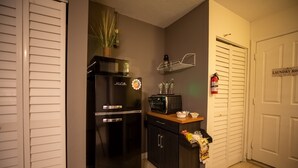 A compact kitchen with a black refrigerator, microwave, and a small countertop with a sink. - Luxurious Pool Cottage Sleep 2 (Port St. Lucie)