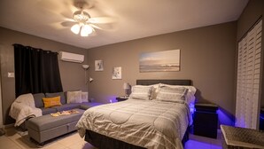 A bedroom with a bed, a sofa, a ceiling fan, an air conditioner, and a window with curtains. - Luxurious Pool Cottage Sleep 2 (Port St. Lucie)