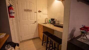 A small kitchen with a sink, a coffee maker, and a fire extinguisher.