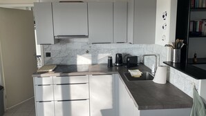 A modern kitchen with white cabinets, a marble backsplash, and a built-in island with a sink and countertop. - Luxe Freistehendes Familie Ferien-haus mit Sauna (Scharendijke)