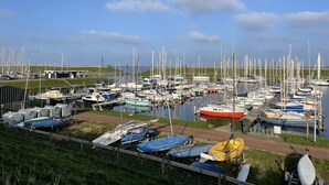 A marina with numerous boats docked, a grassy area, and a clear sky. - Luxe Freistehendes Familie Ferien-haus mit Sauna (Scharendijke)
