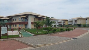 Un bâtiment moderne à plusieurs étages, doté d’une cour dallée et d’une enseigne indiquant les équipements disponibles.