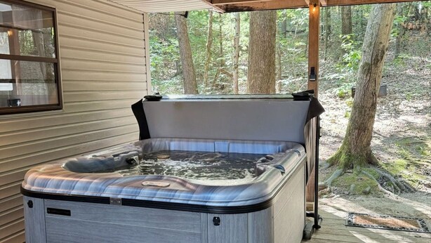 A hot tub on a wooden deck with a view of a forest.