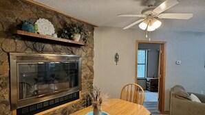 A dining area with a stone wall, fireplace, and wooden table.