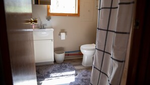 Un baño pequeño con un lavamanos blanco, inodoro y una ventana sobre el inodoro.