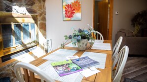 Un comedor con pared de piedra, chimenea y una mesa con papeles y un cartel de bienvenida.