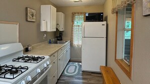 Una cocina compacta con estufa a gas, horno, refrigerador y microondas.