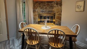 Comedor con chimenea de piedra, mesa de madera y sillas.