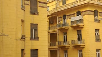 A multi-story yellow building with balconies, air conditioning units, and decorative moldings.