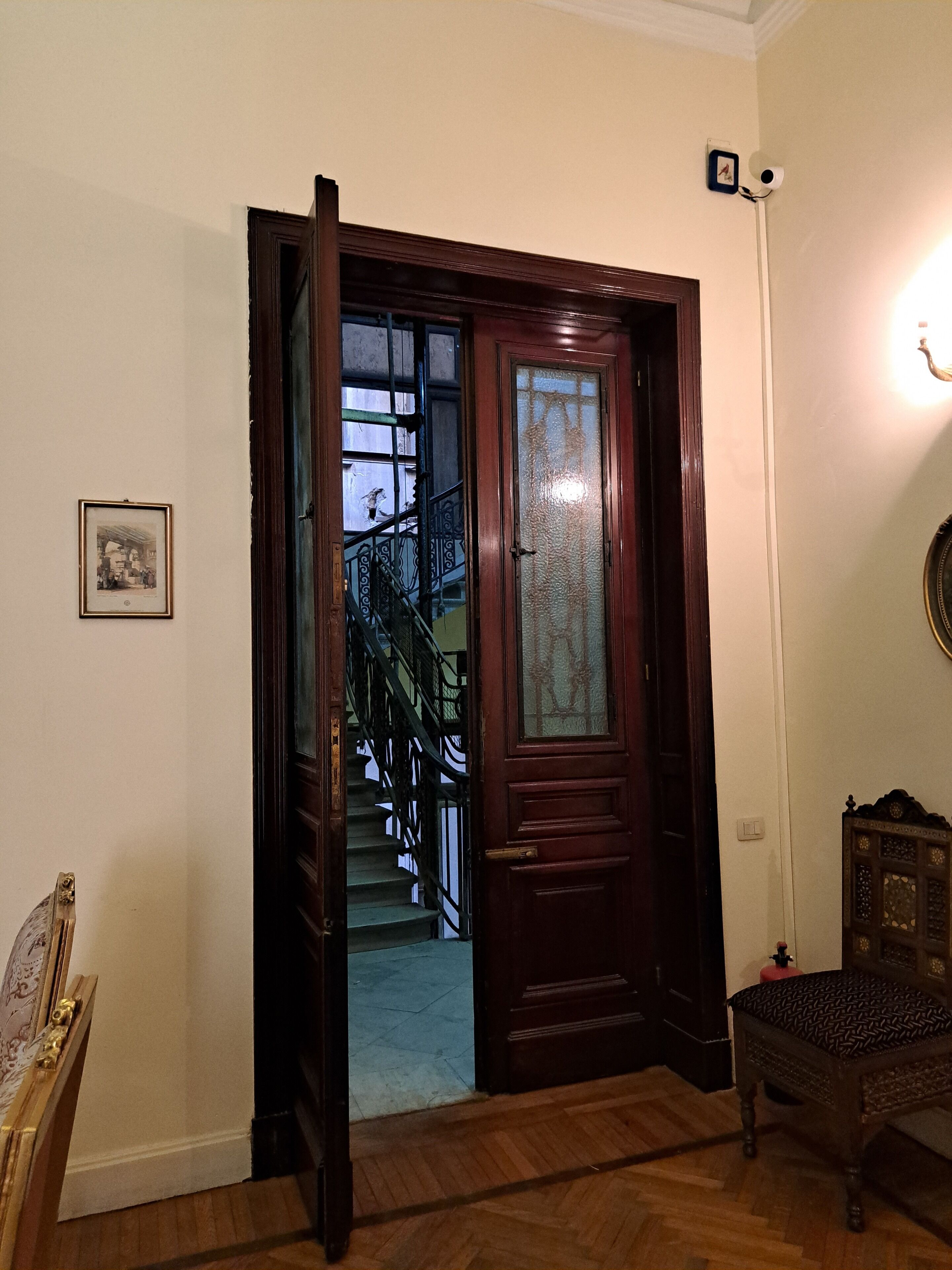 A wooden door leading to a staircase with a metal railing.