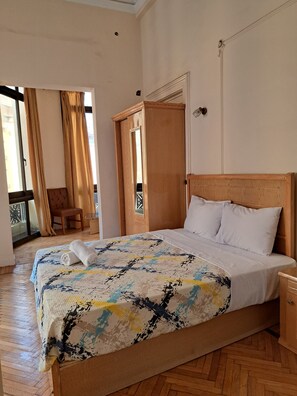 A neatly made bed with a patterned bedspread, a wooden headboard, and a nightstand.