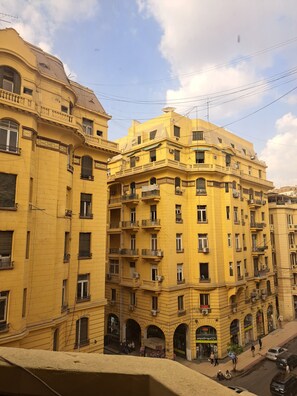 A multi-story yellow building with balconies, arched windows, and a ground-level shop.