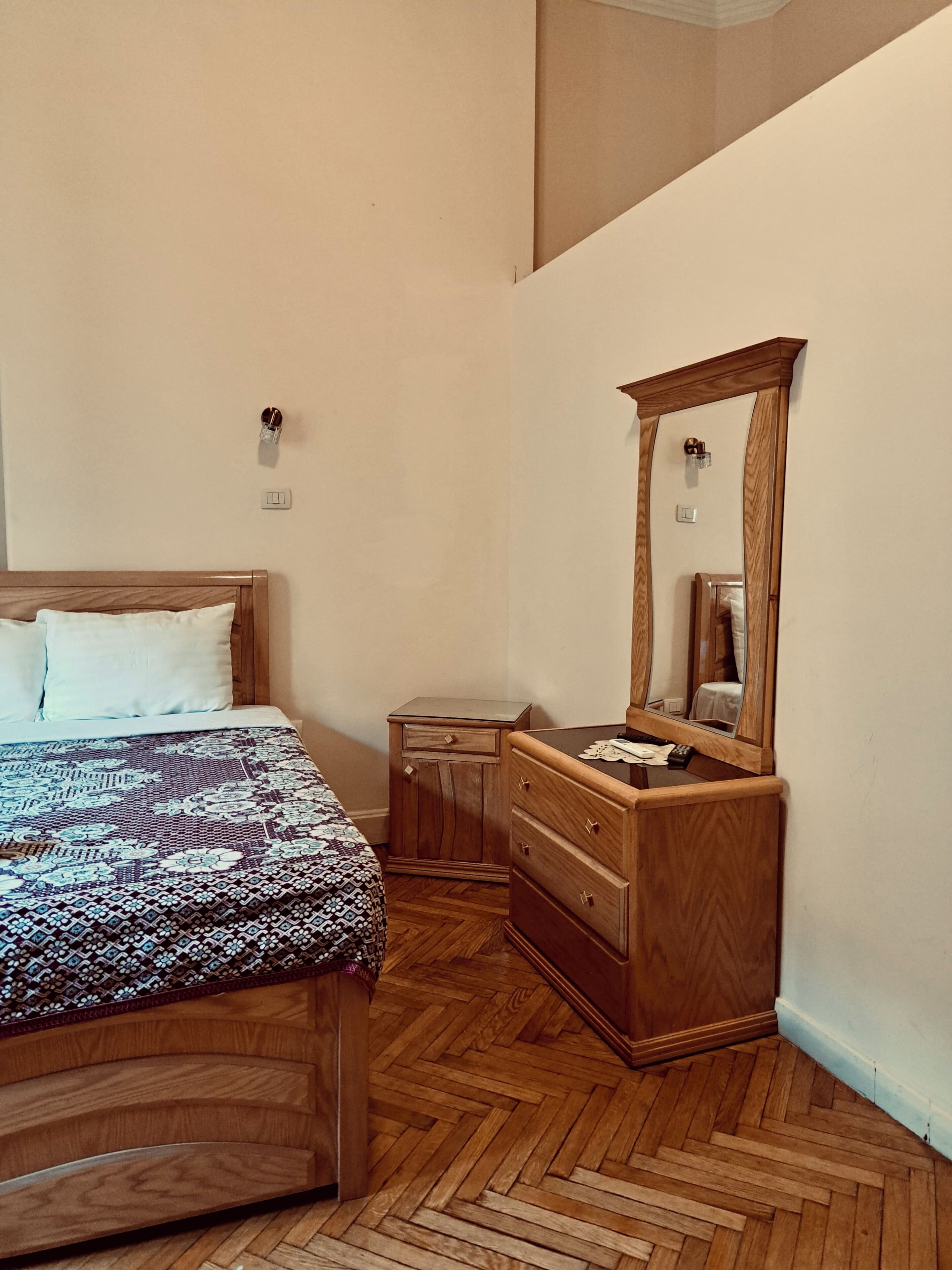 Une chambre à coucher comprenant un lit, une commode, un miroir et une petite table de chevet.