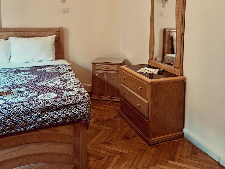Une chambre à coucher comprenant un lit, une commode, un miroir et une petite table de chevet.
