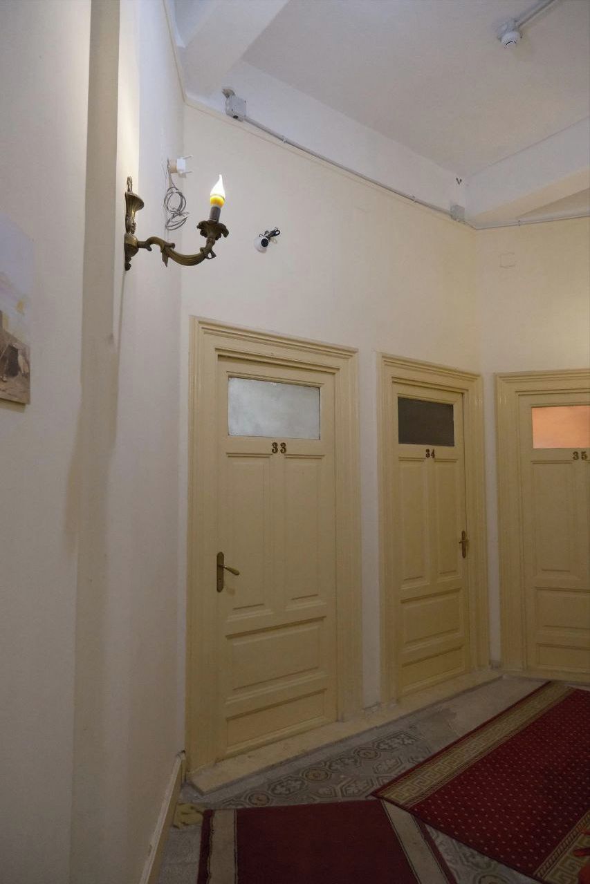 A hallway with three doors numbered 33, 34, and 35, a wall-mounted light fixture, and a patterned carpet.