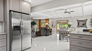 A modern kitchen with stainless steel appliances, a dining area with a table and chairs, and a ceiling fan.