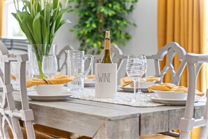 A dining table set with white plates, clear glassware, and a bottle labeled "WINE".