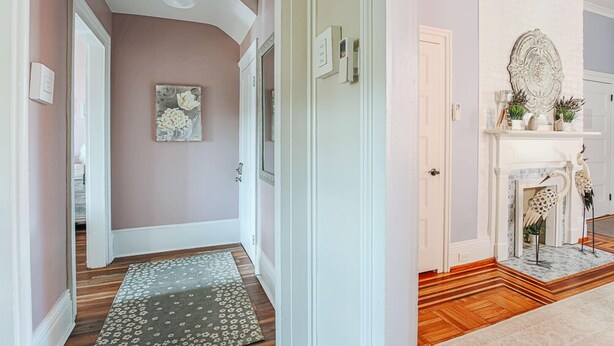 A hallway with a patterned rug, a door, and a fireplace with decorative items. - The Serendipity Suite: Desk, EV, Walk Downtown (Staunton)