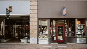 A storefront with a glass door, a sign reading "EXPLORE," and various items displayed outside. - The Serendipity Suite: Desk, EV, Walk Downtown (Staunton)