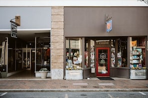 Une devanture de magasin avec une porte vitrée, une enseigne sur laquelle on peut lire « DÉCOUVREZ » et divers articles exposés à l’extérieur.