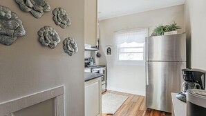 A kitchen with a stainless steel refrigerator, a coffee maker, and decorative wall art. - The Serendipity Suite: Desk, EV, Walk Downtown (Staunton)
