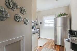 Une cuisine équipée d’un réfrigérateur en acier inoxydable, d’une machine à café et agrémentée d’œuvres d’art décoratives sur les murs.