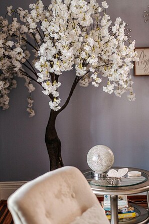 A room with a decorative tree, a round glass table with a silver sphere, and a framed picture on the wall. - The Serendipity Suite: Desk, EV, Walk Downtown (Staunton)