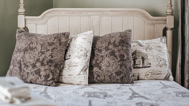 A bed with a wooden headboard and patterned pillows. - The Bons Amis Suite: Chic Decor, Walk Downtown (Staunton)