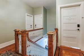 Una escalera con barandillas de madera y un pasamanos blanco que conduce a una puerta con la inscripción 'The Shenandoah Suite'.