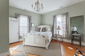 Un dormitorio con cama blanca, candelabro, espejo y puerta.