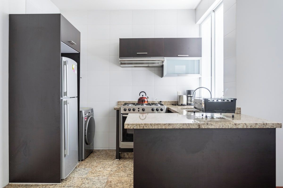 A modern kitchen with a stainless steel refrigerator, a built-in oven, a gas stove, and a microwave.