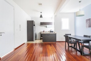 A modern kitchen with a central island, dark cabinetry, and a dining area with a table and chairs.