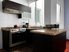 A modern kitchen with a gas stove, oven, microwave, and a granite countertop.