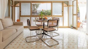 Une pièce comprenant un canapé, une table à manger avec des chaises et de grandes fenêtres dotées de panneaux en verre dépoli.