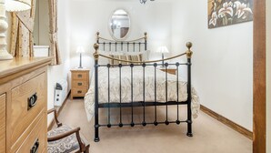 Een slaapkamer met een hemelbed, een houten dressoir en een spiegel.