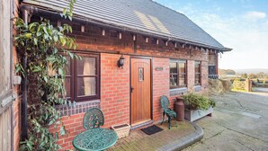 Een bakstenen gebouw met een houten deur, een raam en een bord waarop 'The Dairy' staat.