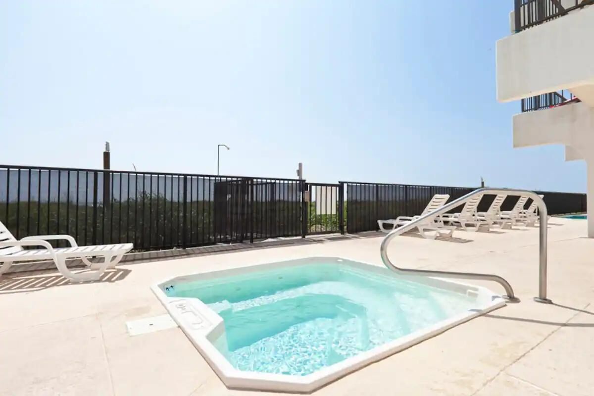Ein Pool auf dem Dach mit freiem Blick zum Himmel, umgeben von weißen Liegestühlen und einem schwarzen Zaun.