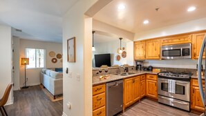 A modern kitchen with wooden cabinets, stainless steel appliances, and a built-in oven. - Newly Designed 2-Story Condo - 1 Block to the Beach! (San Diego)