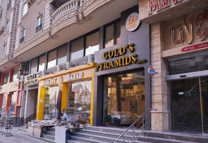 A hotel facade with "GOLD'S PYRAMIDS" signage, a visible entrance, and a staircase leading to the entrance. - Gold's Pyramids Hotel (Giza)