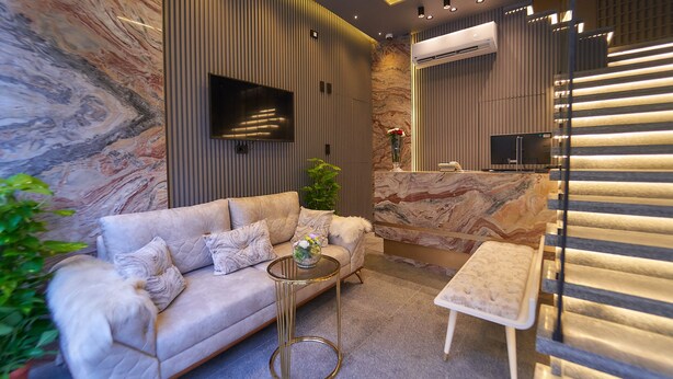 A modern living room with a sofa, a small round table, and a TV mounted on the wall. - Gold's Pyramids Hotel (Giza)