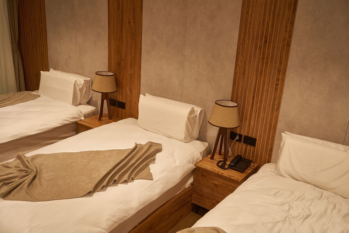 A hotel room with two beds, wooden headboards, and bedside lamps.